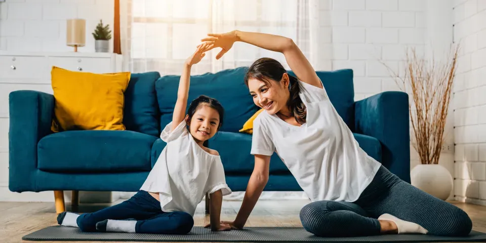 A mother coaches her little daughter in yoga creating a family bond filled with happiness relaxation and togetherness.